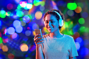 Image showing woman in headphones with smartphone in neon lights