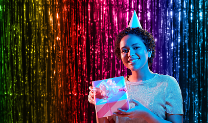 Image showing african woman in party cap with gift box on black