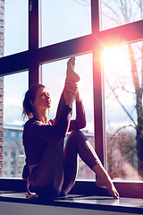 Image showing woman doing yoga exercise on window sill at studio