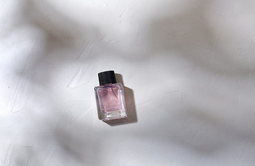 Image showing bottle of perfume on white surface with shadows