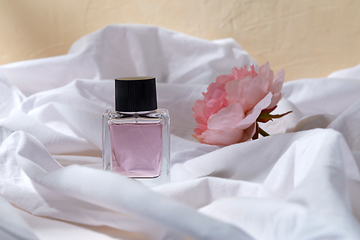 Image showing bottle of perfume and flower on white sheet