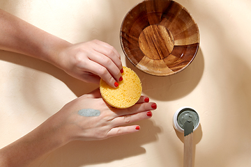 Image showing hands applying blue cosmetic clay mask to skin