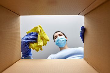 Image showing woman in mask taking cleaning supplies from box