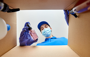 Image showing woman in mask packing parcel box with cosmetics