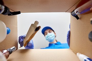 Image showing woman in mask packing parcel box with cosmetics