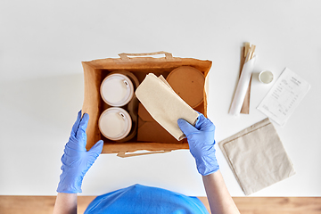 Image showing delivery woman in gloves packing food and drinks