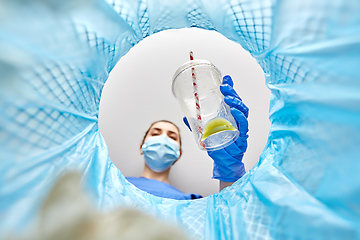 Image showing female doctor throwing plastic cup into trash can