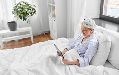 Image showing senior woman with tablet pc in bed at home bedroom