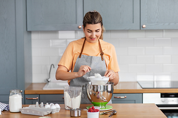 Image showing happy young woman cooking food on kitchen at home