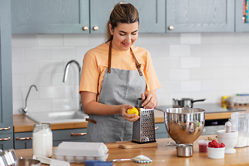 Image showing happy young woman cooking food on kitchen at home