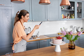 Image showing happy woman photographing cake at home kitchen