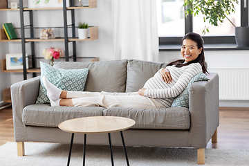 Image showing happy pregnant asian woman sitting on sofa at home