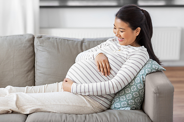 Image showing happy pregnant asian woman sitting on sofa at home