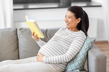 Image showing happy pregnant woman reading book at home