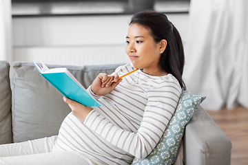 Image showing pregnant woman writing to diary at home