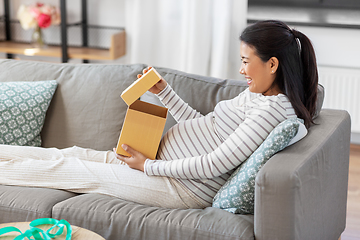 Image showing happy pregnant woman opening gift box at home