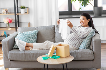 Image showing happy pregnant woman with baby's bodysuit at home