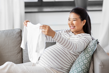 Image showing happy pregnant woman with baby's bodysuit at home