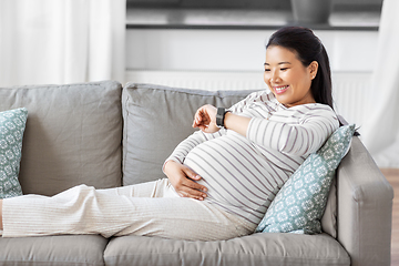 Image showing happy pregnant woman with smart watch at home