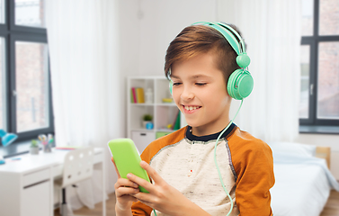 Image showing happy boy with smartphone and headphones at home