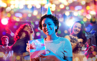 Image showing african woman in party cap with gift box on black