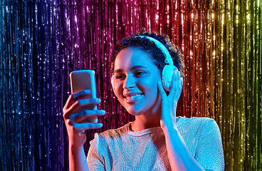 Image showing woman in headphones with smartphone at party