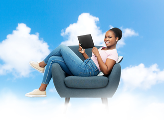 Image showing smiling woman with tablet pc sitting in armchair