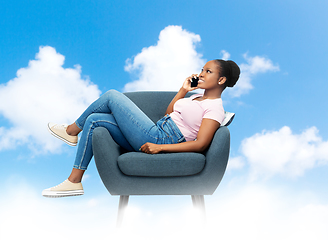 Image showing african woman calling on smartphone in armchair