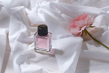 Image showing bottle of perfume and flower on white sheet