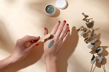 Image showing hands applying blue cosmetic clay mask to skin