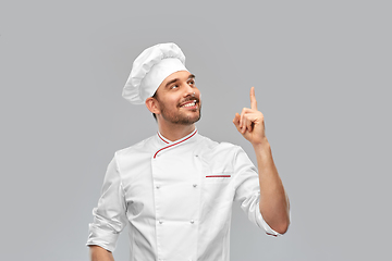 Image showing happy smiling male chef pointing finger up