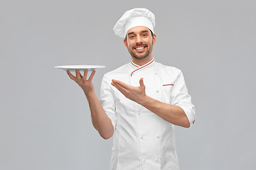 Image showing happy smiling male chef holding empty plate