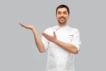 Image showing happy smiling male chef holding something on hand