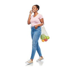 Image showing woman with food in net bag calling on smartphone