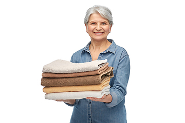 Image showing smiling senior woman with clean bath towels