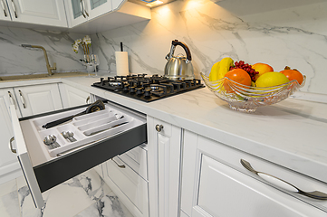 Image showing Open drawers with kitchenware at modern white kitchen