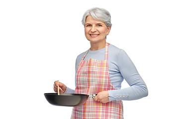 Image showing smiling senior woman in apron with frying pan