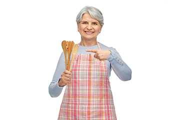 Image showing smiling senior woman in apron with wooden spoons