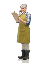 Image showing old female gardener with clipboard calls on phone