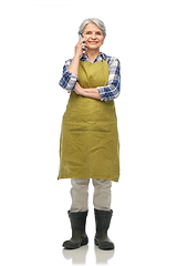 Image showing senior woman in garden apron calling on smartphone