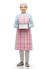 Image showing smiling senior woman in apron with tablet computer
