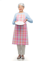 Image showing smiling senior woman in apron with empty plate