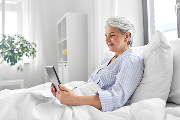 Image showing senior woman with tablet pc in bed at home bedroom