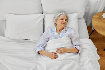 Image showing happy senior woman sleeping in bed at home bedroom