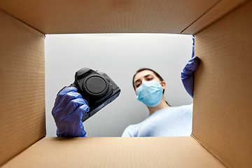 Image showing woman in mask packing camera into parcel box