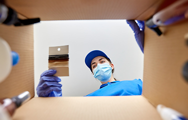 Image showing woman in mask packing hair bands to parcel box