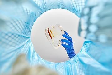 Image showing hand throwing plastic container into trash can