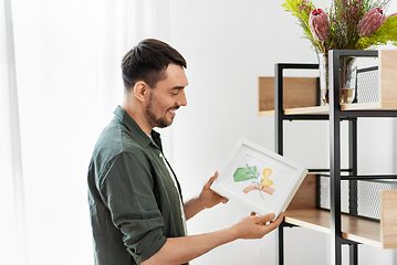 Image showing man decorating home with picture in frame