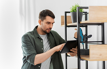 Image showing man with tablet pc at shelf at home