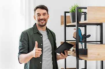 Image showing happy smiling man with tablet pc at shelf at home